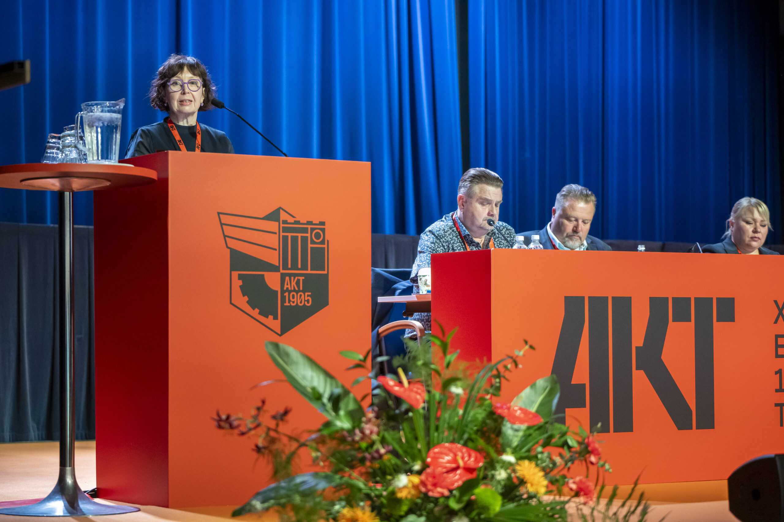Kuva edustajakokouksesta, jossa viestintäpäällikkö Sini Silvàn seisoo puhujapöntön takana.