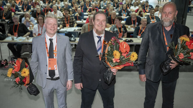 Kuvassa vasemmalla vaaleassa puvussa kravatti kaulassa Niko Blom kukkakimppu kädessään, keskellä tummassa puvussa Ismo Kokko myös kukkakimppu kädessään, oikealla Juha Anttila. Miehet on valittu AKT:n puheenjohtajaksi ja varapuheenjohtajiksi.