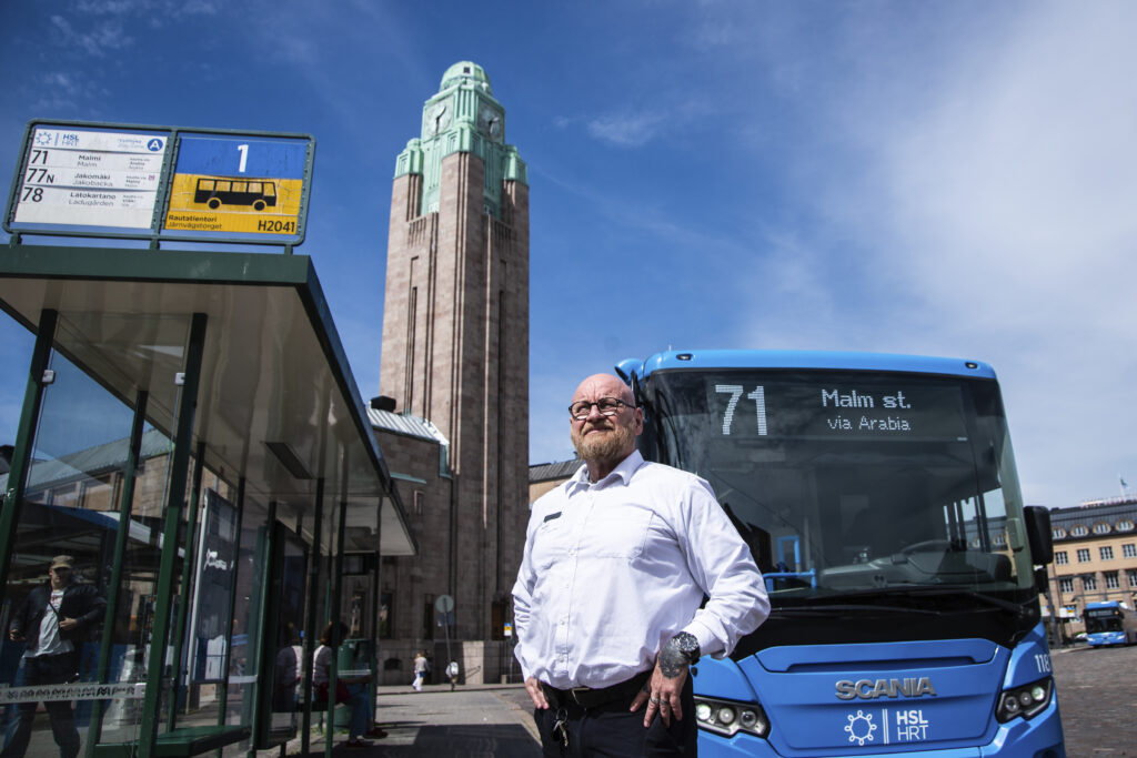 Kuvassa Pertti Piirinen seisoo Rautatietorilla bussin 71 edessä.