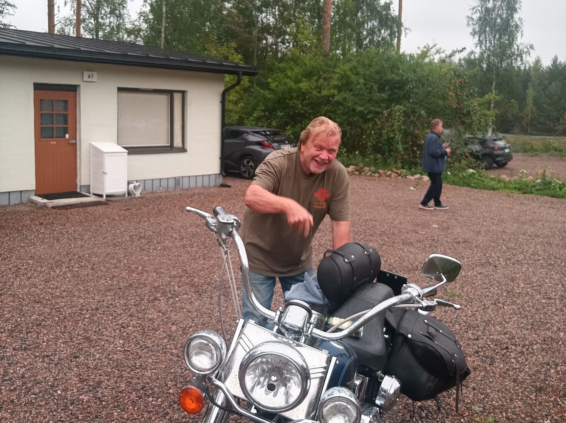 Ilmoinen vaalea henkilö seisoo moottoripyöränsä takana.