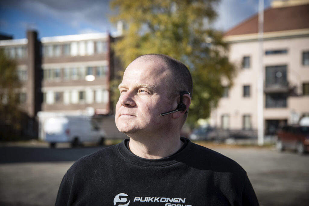 Mies on kääntänyt kasvonsa aurinkoon taustallaan taajamamaisema.