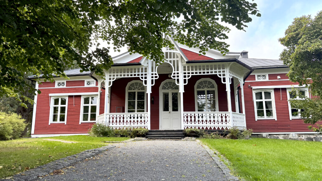 Iso punainen puutalo vehreässä ympäristössä.